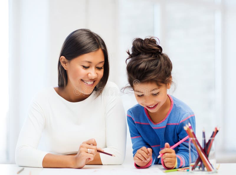 Family, children and happy people concept - mother and daughter drawing