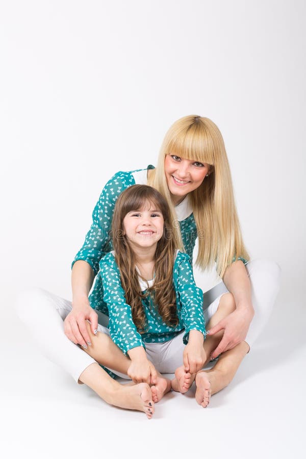 Mother and daughter hug sitting wearing matching outfit