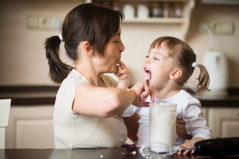 Mother and her child giving each other lick from finger whipping cream.