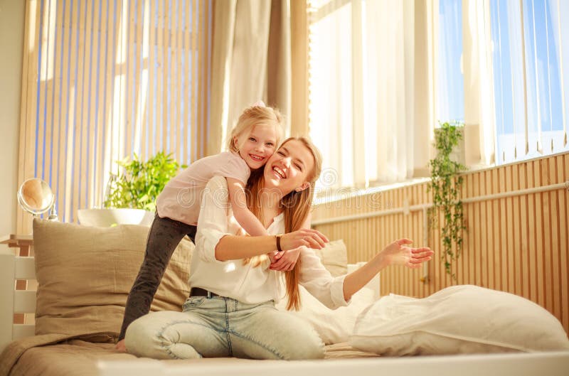 Mother and Daughter Joyfully Hugging at Home on Bed, Happy Family