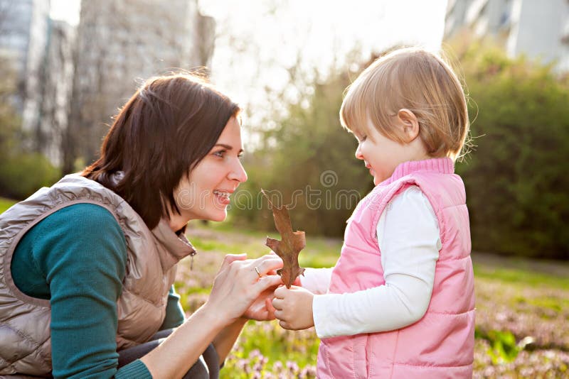 Mother and daughter looking on leaf in park