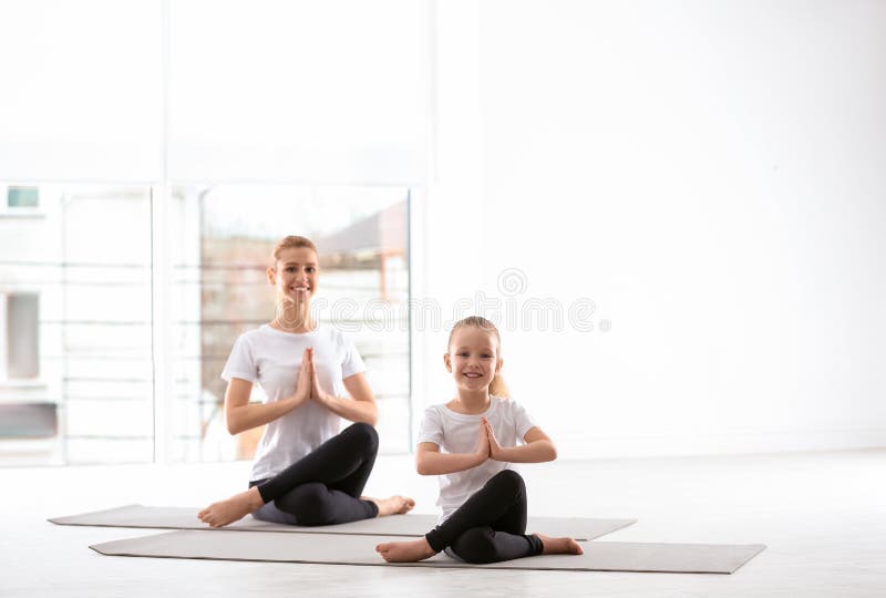 Mother And Daughter In Matching Sportswear Doing Yoga At