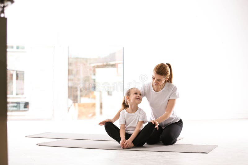 Mother And Daughter In Matching Sportswear Doing Yoga At