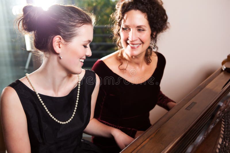 A portrait of a happy mother and daughter playing piano together