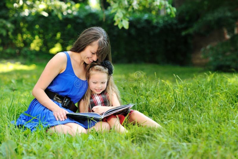 Mother and daughter reading book in a park