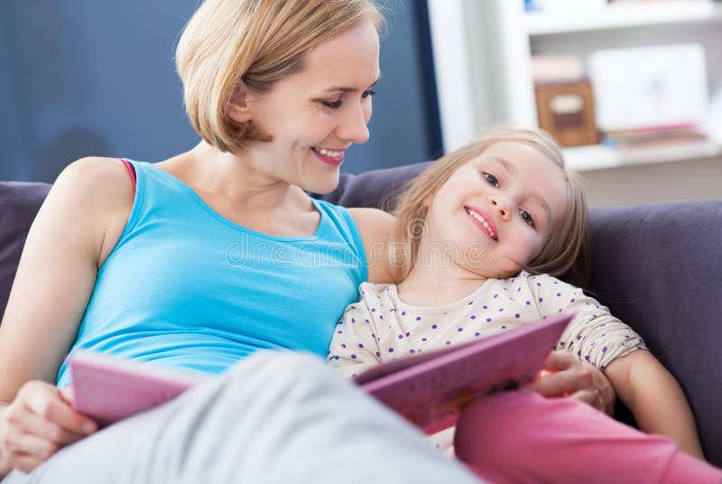 Mother and daughter reading on the couch royalty free stock photography