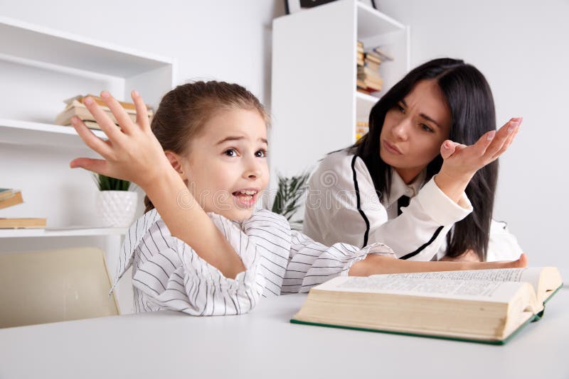 Mother and daughter reading time. Learning together sitting at the table. stock photos