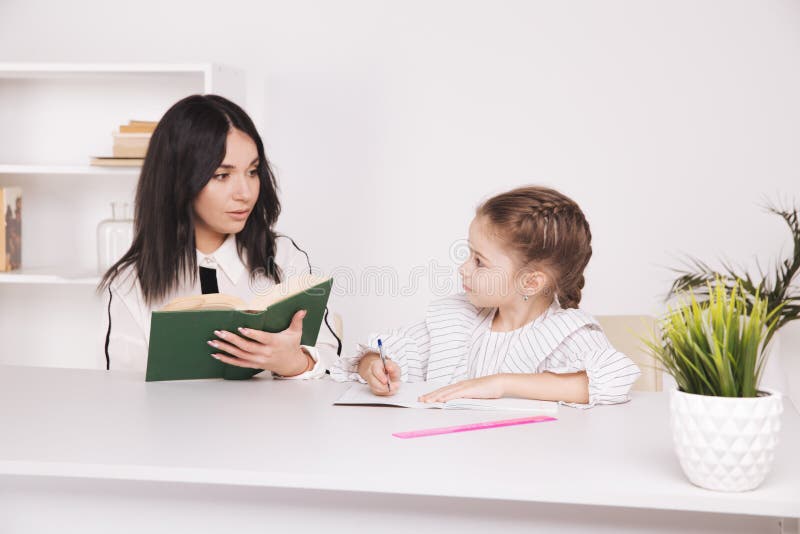 Mother and daughter reading time. Learning together sitting at the table. stock photo