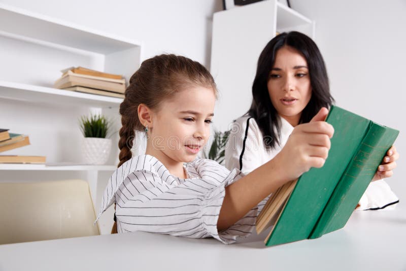 Mother and daughter reading time. Learning together sitting at the table. stock photos