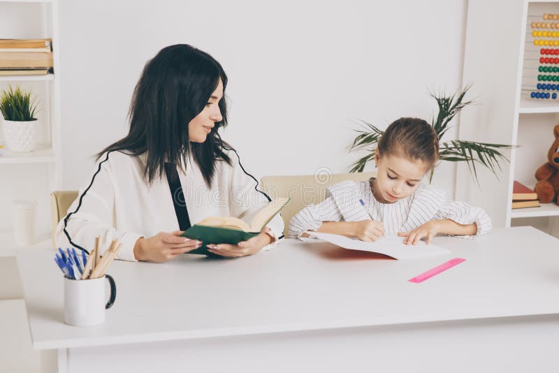 Mother and daughter reading time. Learning together sitting at the table. stock photo