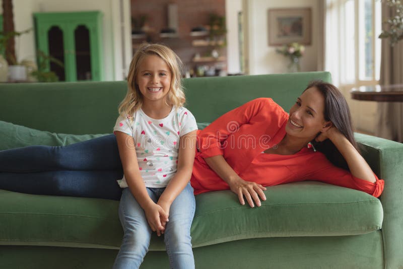 Mother And Daughter Relaxing On A Sofa In Living Room At Home Stock