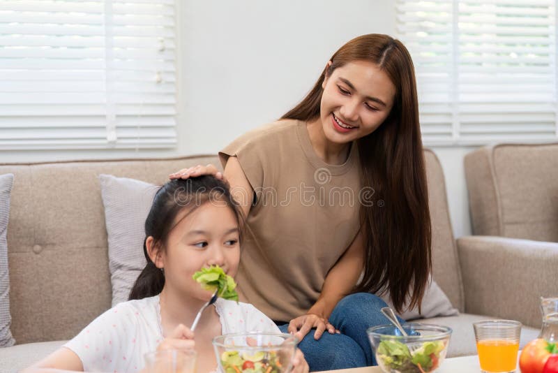 Wellness through healthy eating: Mother and daughter enjoying salad together stock photography