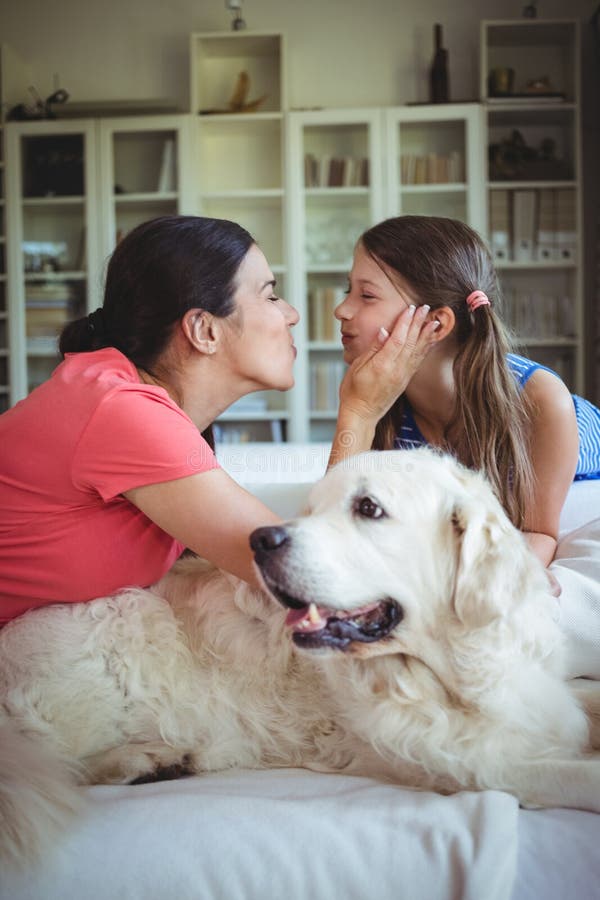 Mother and daughter sitting with pet dog in living room