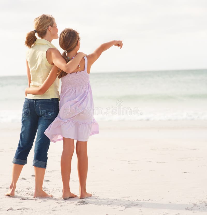 Vista posteriore di una madre e la figlia adolescente in piedi sulla spiaggia, ragazza, rivolta verso il mare.
