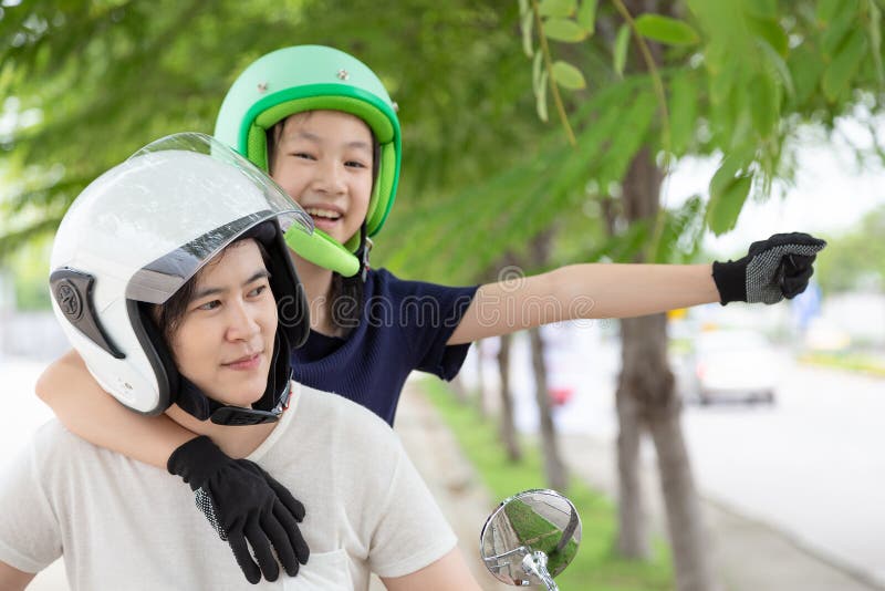 Happy asian family,young women or mother and little child girl or daughter traveling on motorcycle,motorcyclist wearing safe helmet before travel on motorcycle as accident prevention,safety riding concept. Happy asian family,young women or mother and little child girl or daughter traveling on motorcycle,motorcyclist wearing safe helmet before travel on motorcycle as accident prevention,safety riding concept.