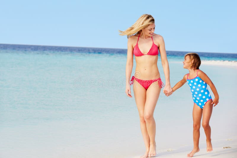 Mother And Daughter Walking On Beautiful Beach