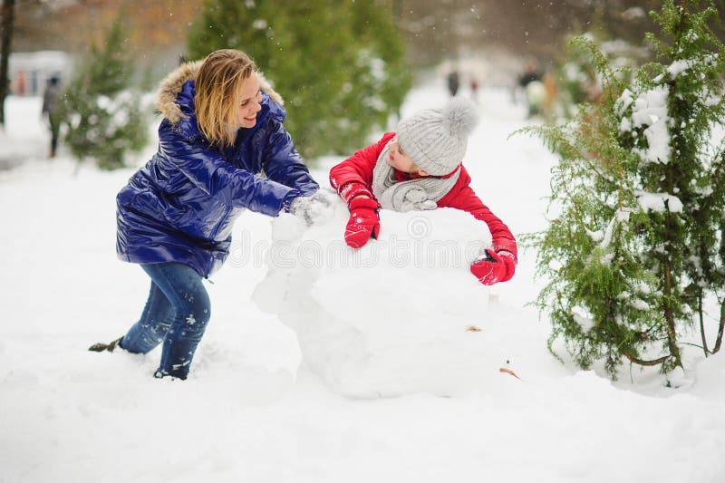 Mother with Daughter of Younger School Age Build a Snowman in the Park ...