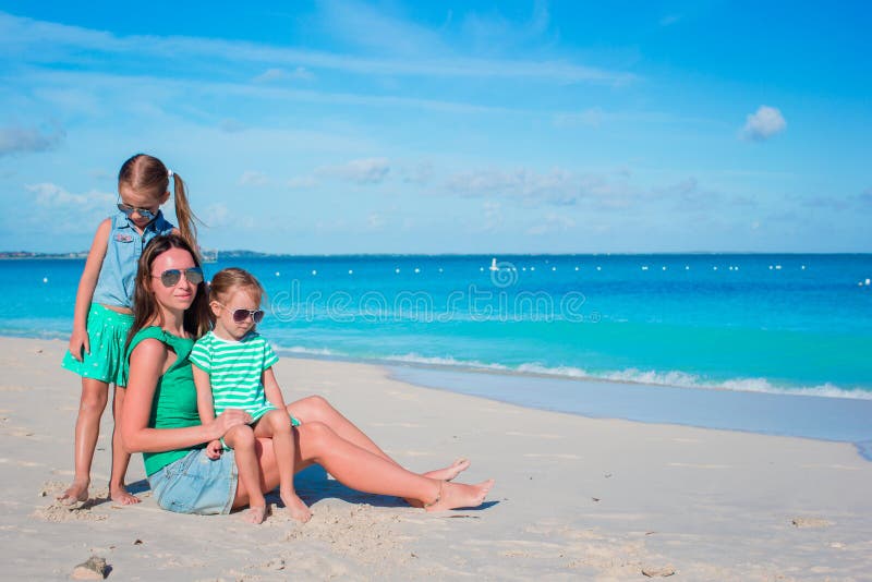 Mother and daughters enjoying time at tropical beach. 