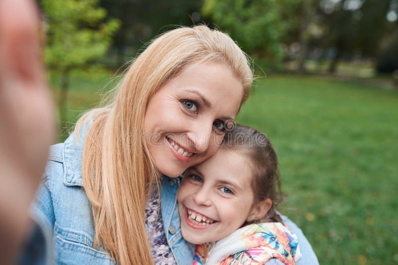 Portrait of a smiling mother and little daughter taking a selfie while enjo...