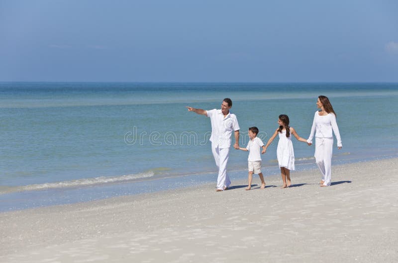 Familia feliz de madre, dos, un hijo, posesión manos divirtiéndose en arena sobre el soleado Playa.