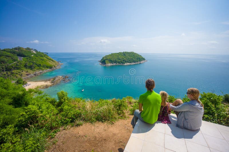 Mother, father and daughter embraces and sit on tropical island