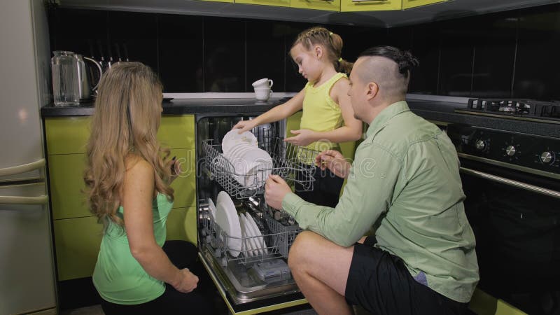 Mother and father teaching daughter learning to use dishwasher. Mistress girl children loading putting dirty dishes in stock images Mother and father teaching daughter learning to use dishwasher. Mistress girl children loading putting dirty dishes in stock images