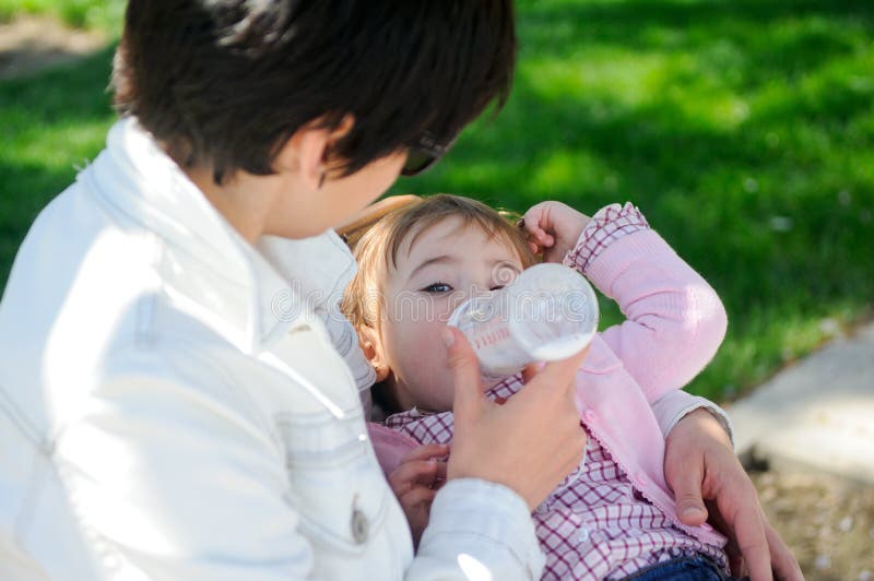 Mother feeding one year baby girl with feeding bottle