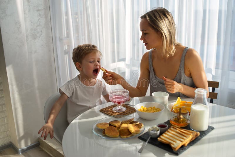 Mother feeds the child Breakfast. A bright Sunny morning.