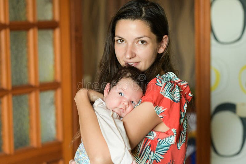 Mother gently hugs the baby. at home. Mom and newborn baby. Mom hugs and holds the newborn baby in her arms, the newborn sleeps in stock photography Mother gently hugs the baby. at home. Mom and newborn baby. Mom hugs and holds the newborn baby in her arms, the newborn sleeps in stock photography