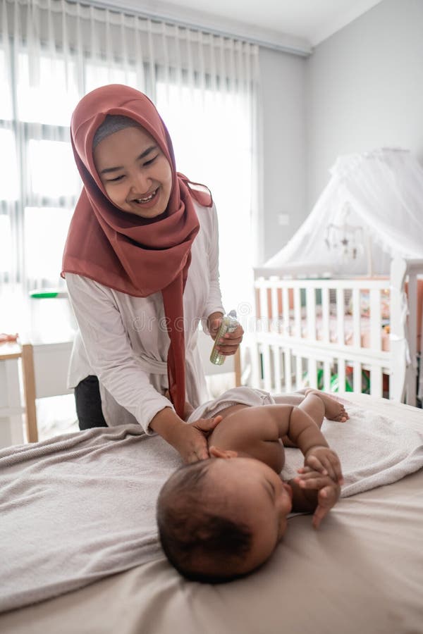 Muslim mother giving a baby boy massage during diaper change