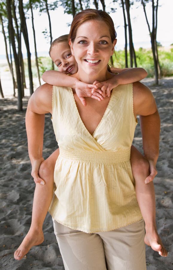 Happy mother giving her son a piggyback ride in the city stock photo