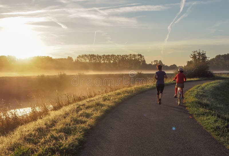 Mother going for a run while accompanied by her son on a bicycle royalty free stock images Mother going for a run while accompanied by her son on a bicycle royalty free stock images