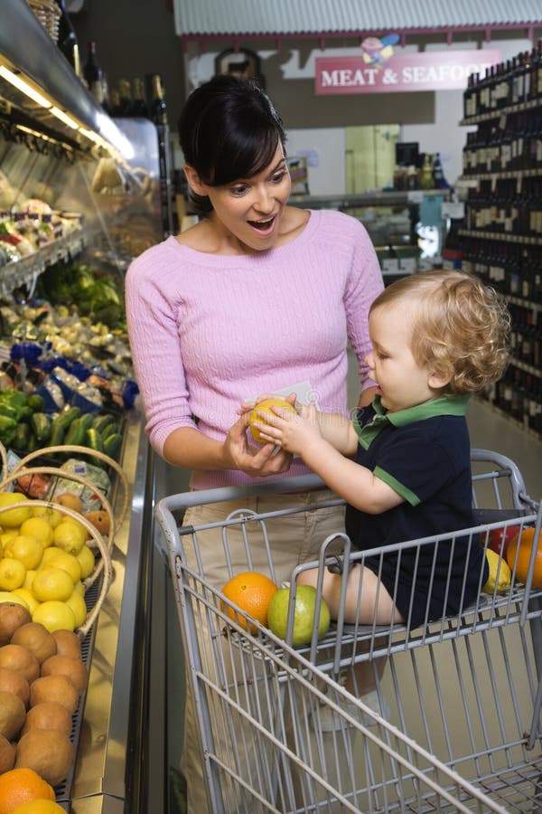 Caucasian mid-adult woman grocery shopping for fruit with young male toddler. Fruit scene stock images, royalty-free photos and pictures
