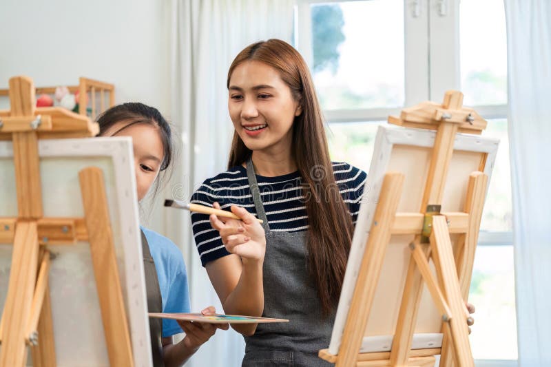 Creative bonding through art: Mother guiding daughter in painting royalty free stock photos