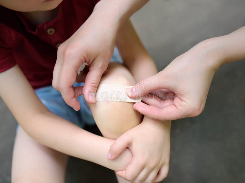Mother hands applying antibacterial medical adhesive plaster on child`s knee after falling down royalty free stock images Mother hands applying antibacterial medical adhesive plaster on child`s knee after falling down royalty free stock images