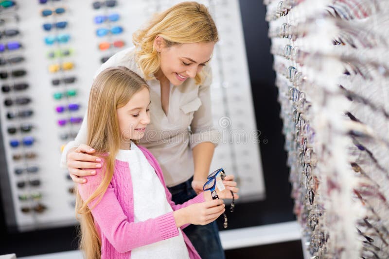 Mother help her girl to choose good frame for eyeglasses stock photos Mother help her girl to choose good frame for eyeglasses stock photos