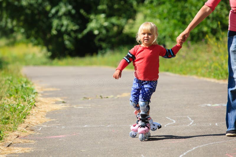 Mother helping little daugther to roller skate