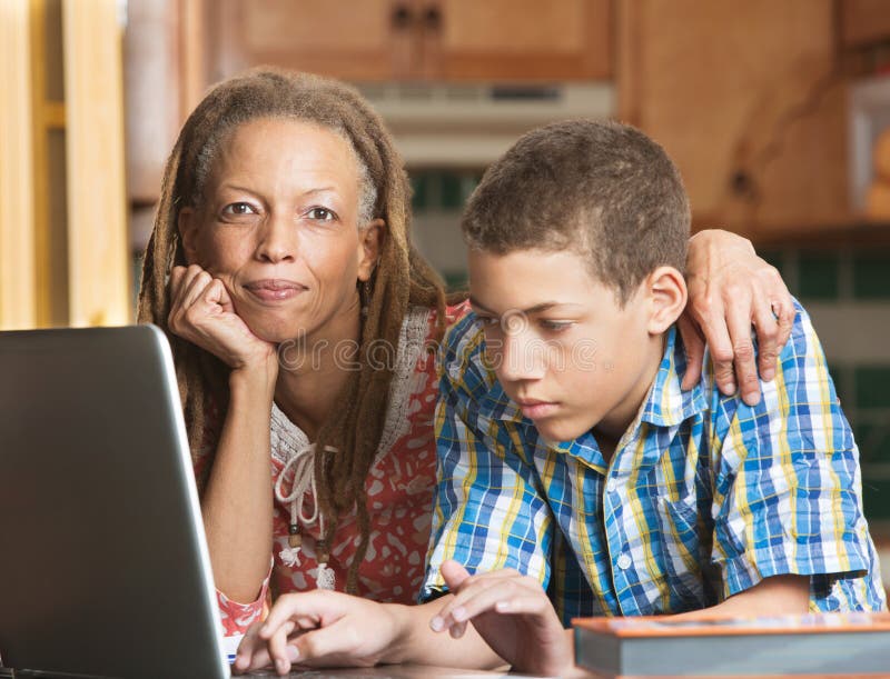 Mother helps teenage son with homework in kitchen