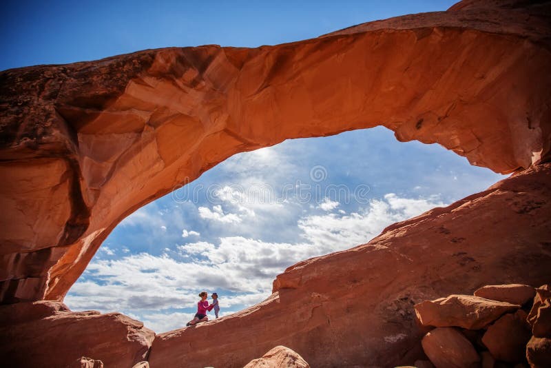 Mother with her baby son stay below Skyline arch in Arches National Park in Utah, USA