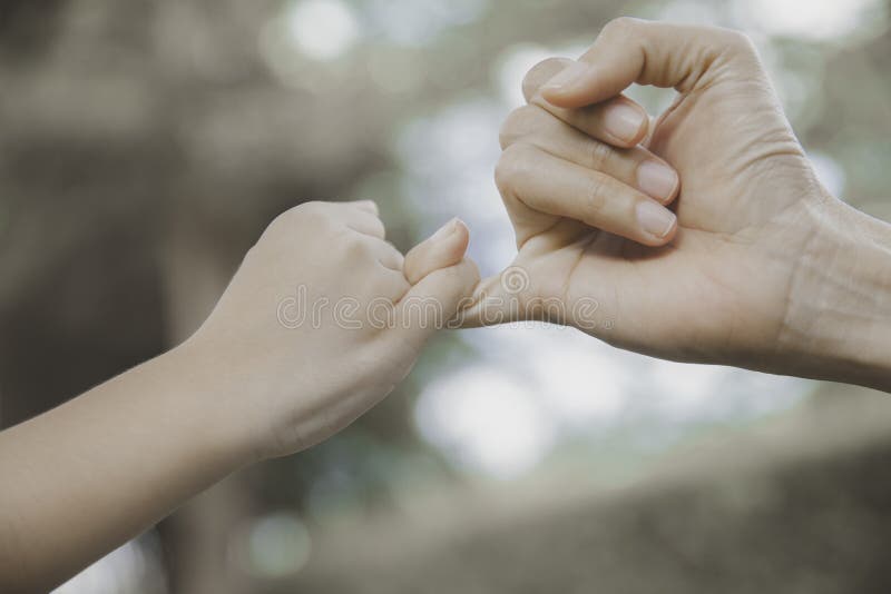 Mother and her child hooking their fingers to make a promise