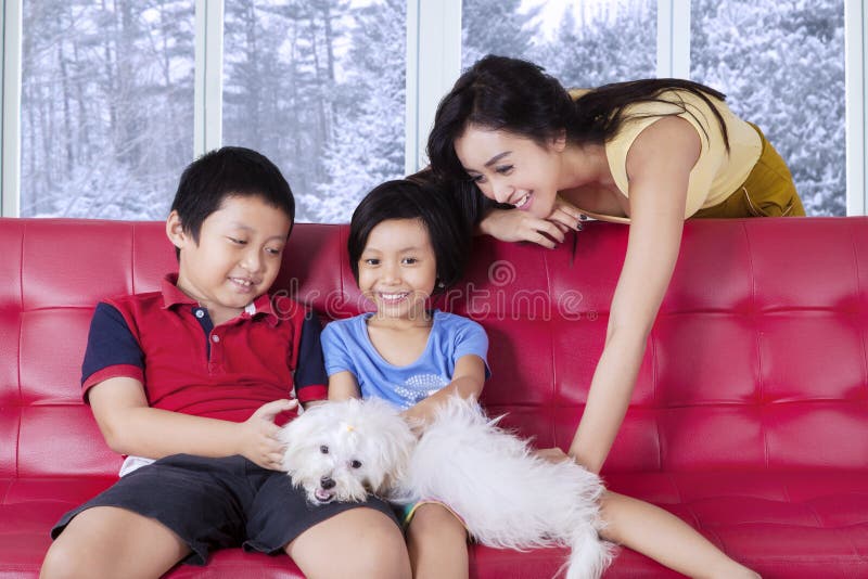 Mother and her children playing dog on sofa
