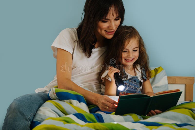 Mother and her little daughter are reading book in bed before going to sleep royalty free stock images Mother and her little daughter are reading book in bed before going to sleep royalty free stock images