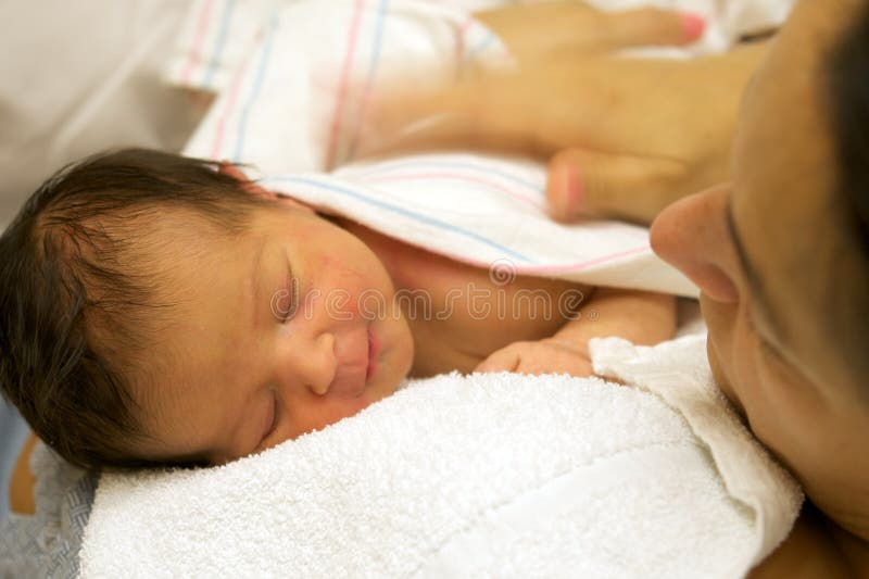 Latin mother holding her newborn baby girl as she sleep peacefully in a hospital room. Latin mother holding her newborn baby girl as she sleep peacefully in a hospital room