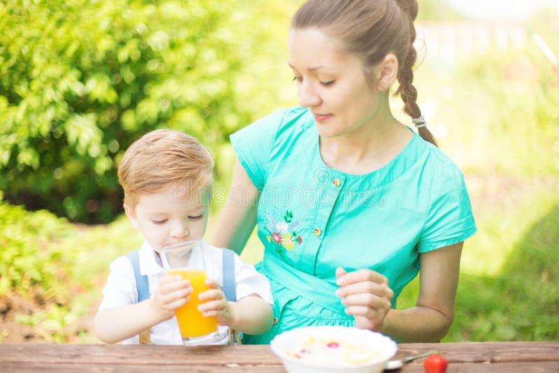Mother and her son on holiday at a picnic. Boy is drinking orange juice. Happy family relaxing in nature royalty free stock photo Mother and her son on holiday at a picnic. Boy is drinking orange juice. Happy family relaxing in nature royalty free stock photo
