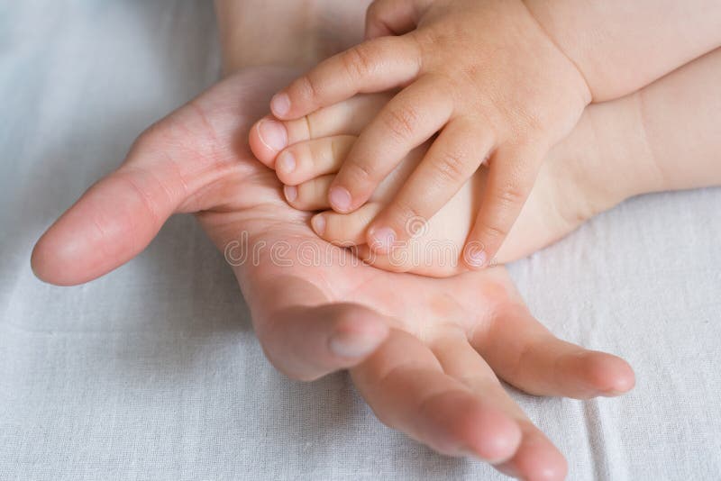Mother is holding baby arm and foot