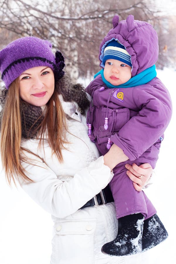 Mother holding a baby, snow, winter park