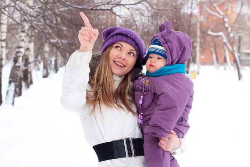 Mother holding a baby, snow, winter park