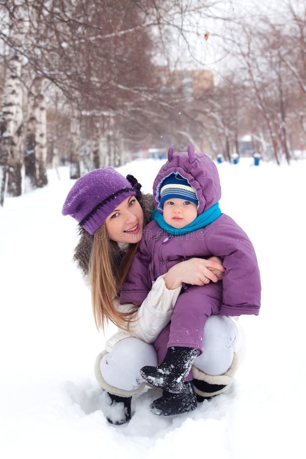 Mother holding a baby, snow, winter park, walk