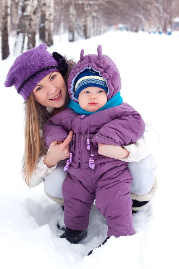 Mother holding a baby, snow, winter park, walk