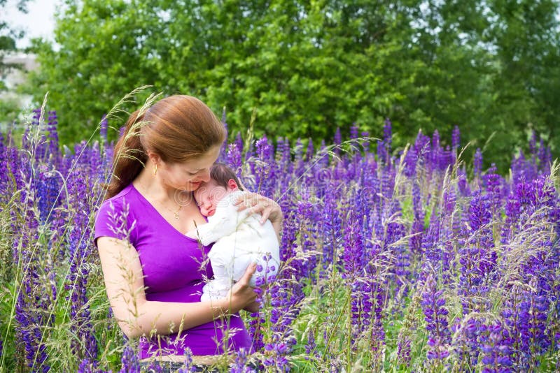 Mother holding her newborn baby in purple flower field